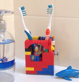 Photo of bathroom sink counter with soap dispenser, plastic shark toy, and toothbrush holder made from Legos.